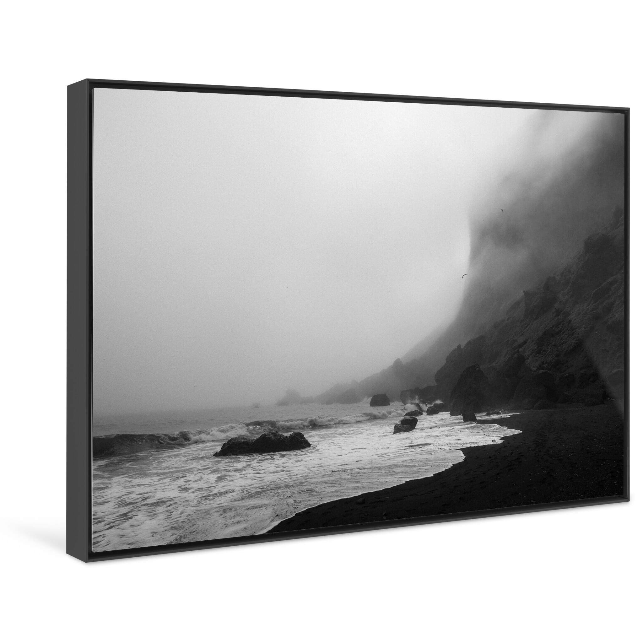 Framed photo print of minimal coastal scene with cliffs rising from black sand in fog